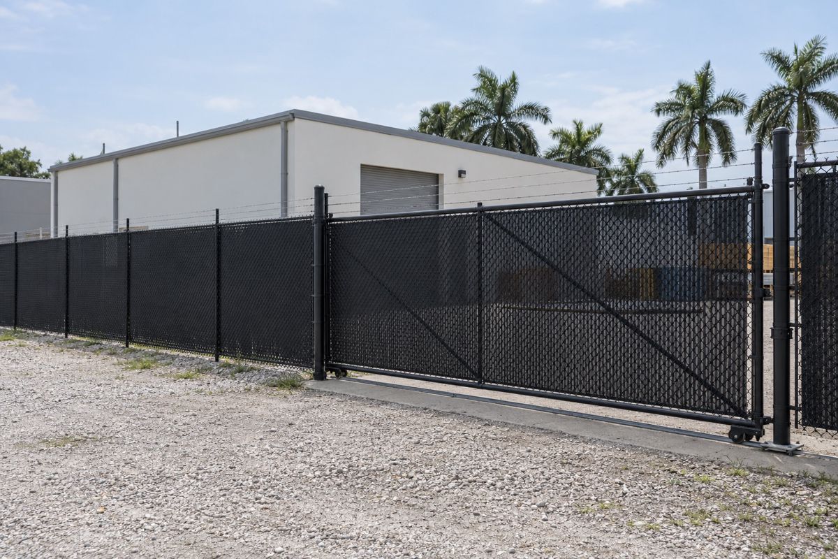 Black chain link fence with a rolling gate around a warehouse yard